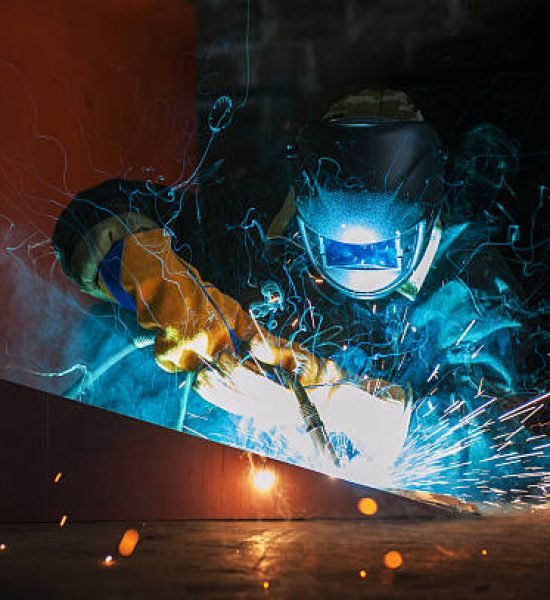 worker welding metal with sparks at factory