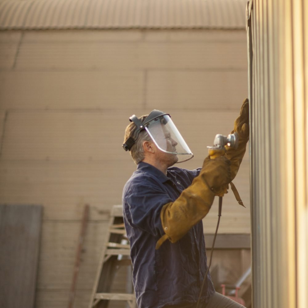 Welder using power tool on shipping container